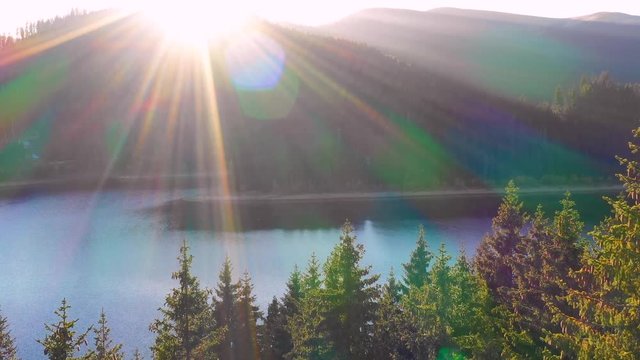 Autumn color forest, aerial view over colorful autumn trees, towards lake. Mountain lake and forest in autumn season. Beautiful sun light. Mountain lake with turquoise water in fall season. October. 
