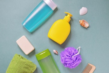 Flat lay organic bath products photo. Shampoo, liquid soap, shower gel, green towel, purple sponge, wooden comb and seashells