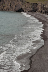 Rocks formation on Dyrholaey cape with black sand beach near  Vik town, Iceland in summer on sunny day, vintage effect with some grain