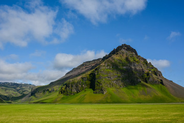 Mountain near Eyjafjallajokull volcano area in Iceland. Green field, blue sky, sunny summer day.