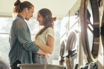Couple in love standing together listening to music in laundry r