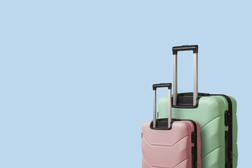 Two Suitcases on wheels on a blue background. Сoncept of travel, a vacation trip, a visit to relatives. Pink and Green color