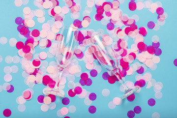 Pink confetti and empty portions for champagne on a blue background. Party and holiday concept. Flat lay, top view
