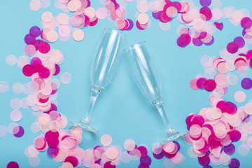 Pink confetti and empty portions for champagne on a blue background. Party and holiday concept. Flat lay, top view