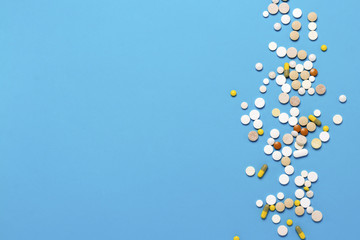 Pills of different colors and sizes on a blue background. Concept of the pharmaceutical industry, medicine, treatment and recovery after illness. Flat lay, top view