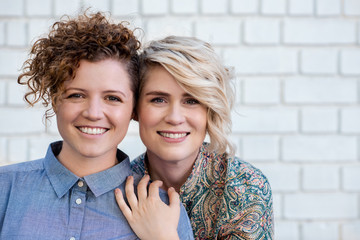 Smiling young lesbian couple standing close together outside - obrazy, fototapety, plakaty