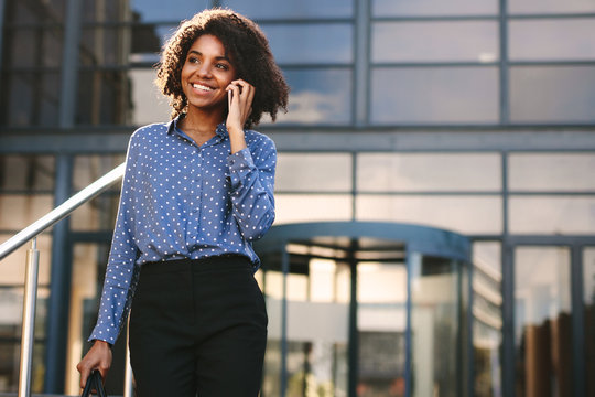Businesswoman walking outdoors and talking on phone