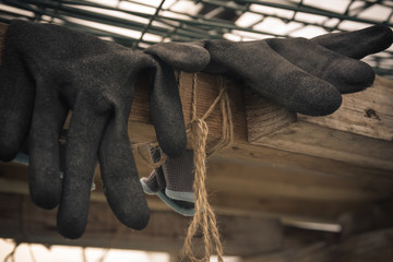 Close up of rubber gloves of a farmer lying in greenhouse. Hard work concept. Vintage style.