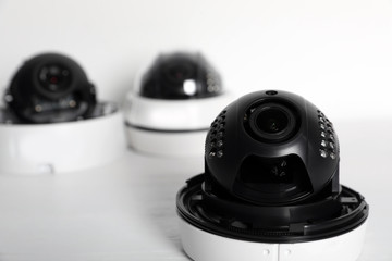 Modern CCTV cameras on table against light background. Home alarm system