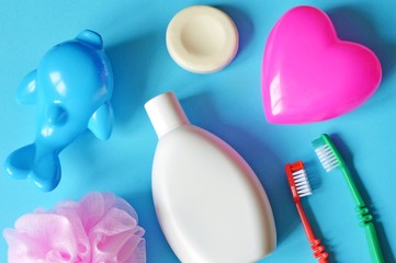 Flat lay shampoo, two colorful toothbrush, soap, sponge and pink heart shape box