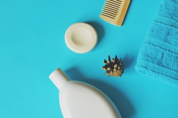 Flat lay photo shampoo, soap, wooden comb and terry towel on a blue background