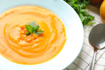 Plate with tasty pumpkin soup on table, closeup view