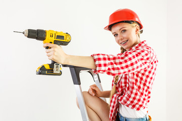 Woman using drill on ladder