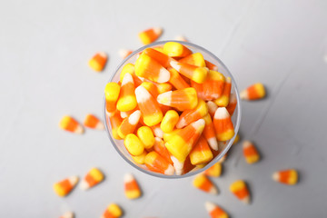 Glass of tasty candy corns on gray background, top view