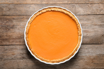 Fresh delicious homemade pumpkin pie on wooden background, top view