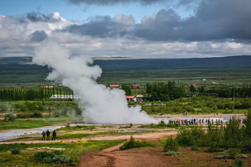 Fototapeta premium Eruption of Strokkur geyser in Iceland in summer with many tourists in the background