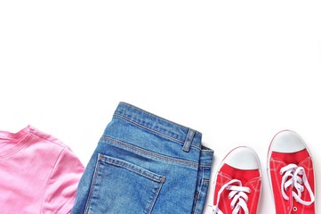 Flat lay fashion outfit. Pink t-shirt, blue jeans and red gumshoes. Free space for text, mockup