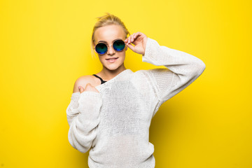 Portrait of smiling beautiful blonde girl in sunglasses against of yellow background.Isolated