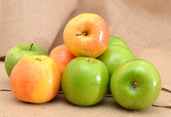 different colors apples on burlap  background