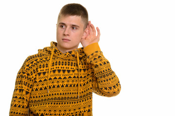 Young curious Caucasian man listening while cupping ear