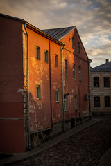 Red house in the old town of Jekabpils, Latvia with sun beams on it and beautiful sky at sunset.