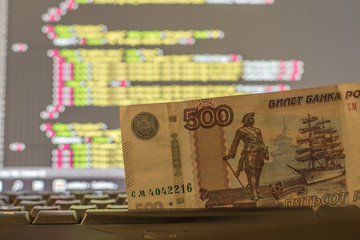 Money on the keyboard and computer display with code on the background