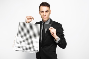 Portrait of happy young businessman in black suit, with packages, for shopping, holding credit card isolated on white background. Black Friday