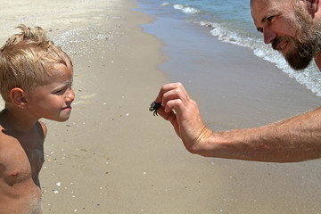 A man shows a child caught a crab