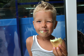 Cheerful white boy got dirty eating ice cream