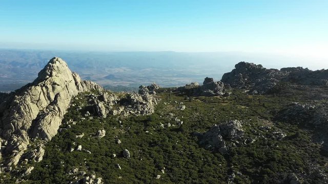 Video from above, aerial view of a beautiful valley surrounded by granite mountains and green vegetation, Monte Limbara, Sardinia, Italy.