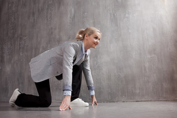 Young woman in business suit and sneakers. At a low start, ready to run a long distance