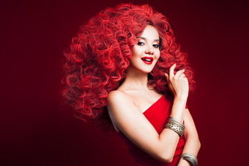 Portrait of beautiful young woman with red hair on red background