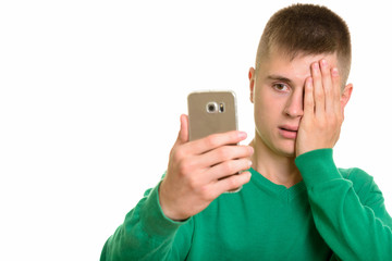 Young Caucasian man holding mobile phone looking stressed