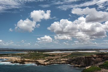 Capo Mannu Cliffs and beach against blue sea or ocean with blue sky and cumulus clouds. Shot in...