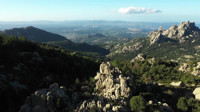 Video from above, aerial view of a beautiful valley surrounded by granite mountains and green vegetation, Monte Limbara, Sardinia, Italy.