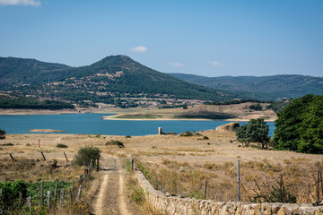 Fototapeta premium Landscape view of Lago Lerno lake and mountain range in the morning. Clear blue sky on a sunny day, turquoise blue water and drive way in the foreground. Nobody in the scene.