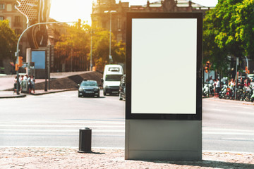Outdoor empty informational board placeholder with a busy road behind; white blank city billboard mockup; vertical blank advertising banner template on the sidewalk with the road crossing behind