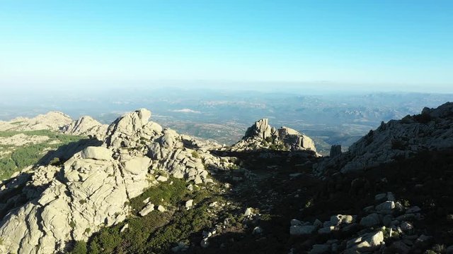 Video from above, aerial view of a beautiful valley surrounded by granite mountains and green vegetation, Monte Limbara, Sardinia, Italy.
