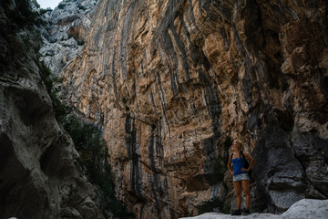 Young woman standing in canyon and looking at the top of canyon. Shot in Gola Su Gorropu canyon, Sardinia, Italy - important natural site in Sardinia. 