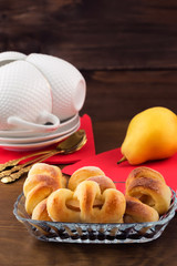 Pastry dough with sliced pears inside in a glass plate on a wooden background.
