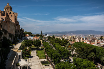 View on the city of Cagliari, the capital of Sardinia, Italy from above. Colorful houses, palms, blue sky on a sunny day and mountains in the background. Nobody in the scene.