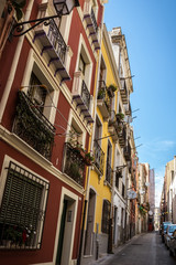 Fototapeta premium Colorful houses in the narrow streets of Cagliari in Sardinia, Italy. Facades of houses in red and yellow, beautiful blue sky on a sunny day. Nobody in the scene.