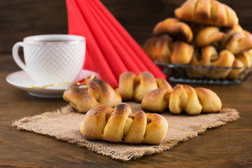 Preparation for Breakfast-pastries with filling, tea in a white mug, folded triangle red napkins.