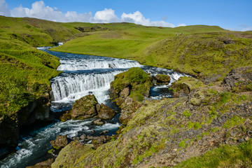 Fototapeta na wymiar Countryside with trail near famous Skogafoss Waterfall, Iceland on sunny summer day and blue sky