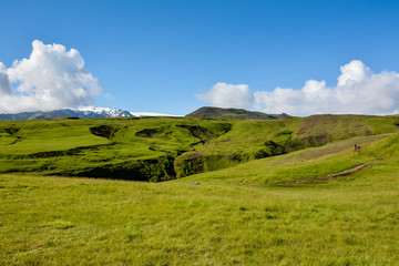 Fototapeta premium Rural landscape with green meadow and trail on sunny summer day and blue sky in Iceland, near Skogafoss