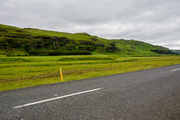 Empty straight asphalt road with view to mountain on overcast summer day in Iceland.