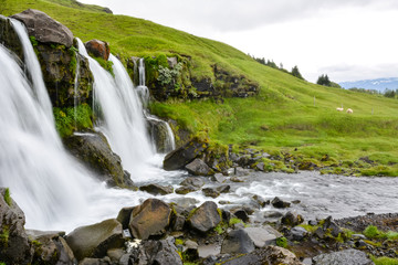 Naklejka na ściany i meble Thorsteinslundur waterfall in motion blur on overcast summer day in Iceland.