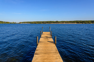 View from long wooden pier onto Wannsee lake and Havel river during sunny day, clear sky in autumn in Berlin, Germany.
