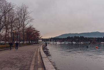 Vancouver, British Columbia/Canada - December 24 2017: Coal harbour bay - waterfront in downtown park with some people walking.