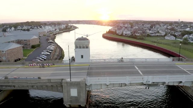 Aerial drone shot over a bridge and a river heading out into the Atlantic Ocean through the city buildings of Belmar, New Jersey.